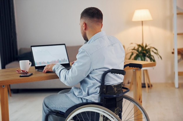 Lavoratore d'affari l'uomo disabile in sedia a rotelle è a casa