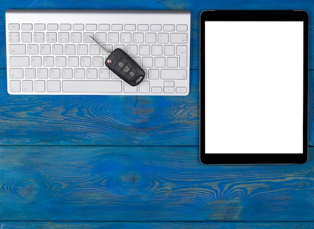 Business Workplace with wireless keyboard, tablet computer and car keys on blue wooden background. Office desk with copy space. Empty space for text