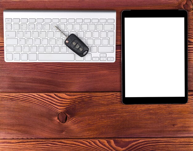 Business Workplace with wireless keyboard, tablet computer and car keys on red wooden background. Office desk with copy space. Empty space for text