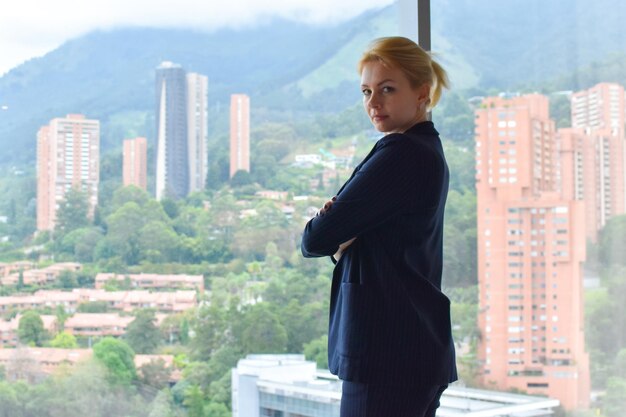 business young woman in suit stands at the panorman window with city view