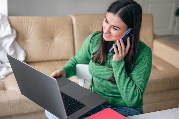 Photo business young woman with smartphone and laptop at home