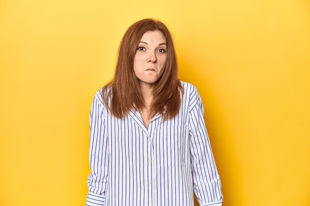 Businessdressed redhead formal studio shot shrugs shoulders and open eyes confused