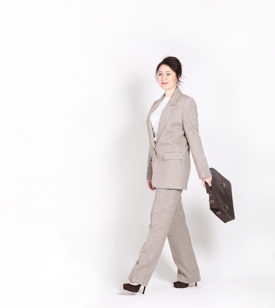 A businesslike young woman in a pantsuit with a briefcase and a smartphone