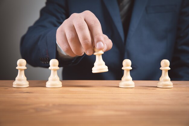 businessma with chess pieces on wooden surface