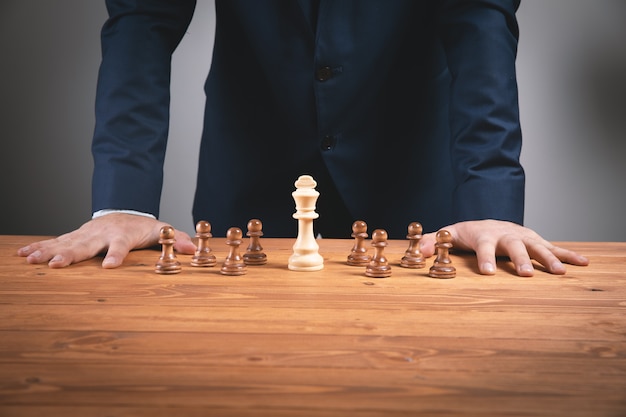 businessma with chess pieces on wooden surface