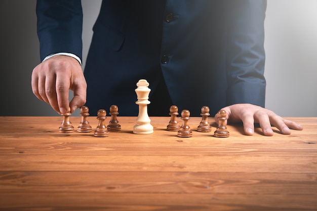 businessma with chess pieces on wooden surface