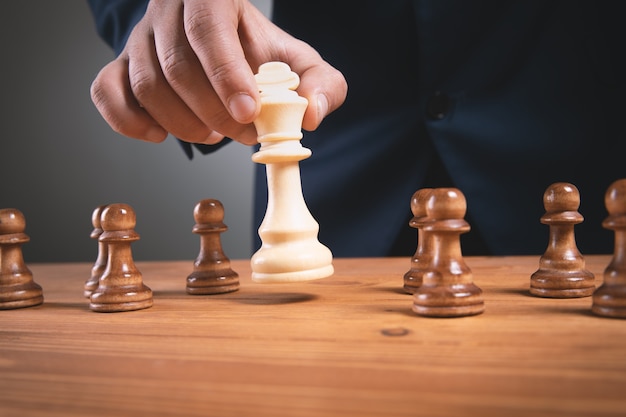 businessma with chess pieces on wooden surface