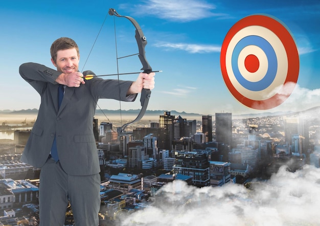 Businessman aiming with bow and arrow at target over cityscape