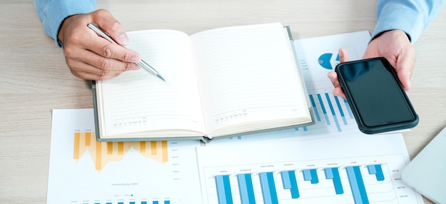 Businessman analysis the chart with smartphone at the office for setting challenging business goals And planning to achieve the new target.