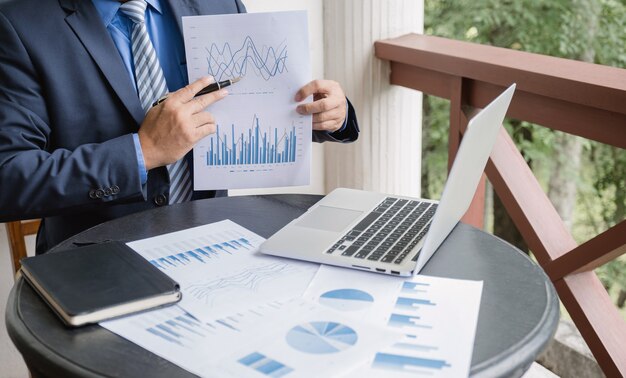 Businessman analysis graph with laptop at home office for setting challenging business goals