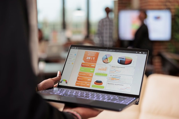 Businessman analyzing charts and graphs on laptop, using website browser. Checking startup information on diagram to create presentation on computer in boardroom, using online research data. Close up.