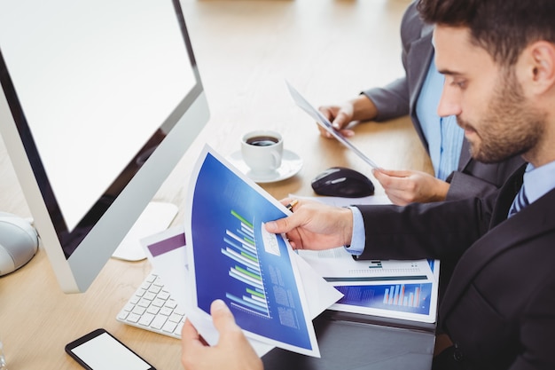 Businessman analyzing graph at computer desk