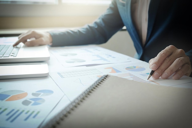 Businessman analyzing graphs and using laptop at desk