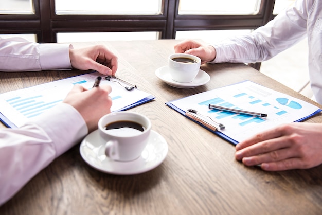 Businessman analyzing graphs with cup of coffee.