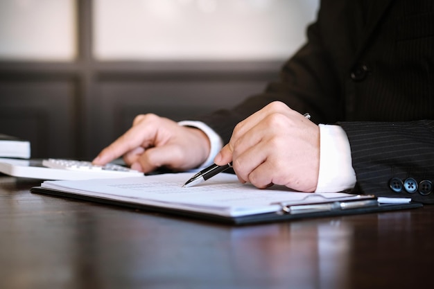 Businessman analyzing investment charts and pressing calculator buttons over documents Accounting Concept