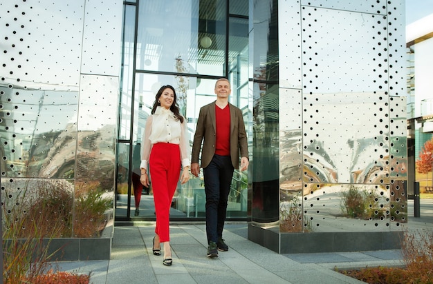 Photo businessman and asian business woman walking near office full length confident  successful couple