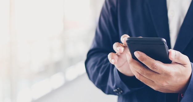 Бизнесмен Азии с помощью телефона для подставки и текстовые сообщения на своем мобильном телефоне