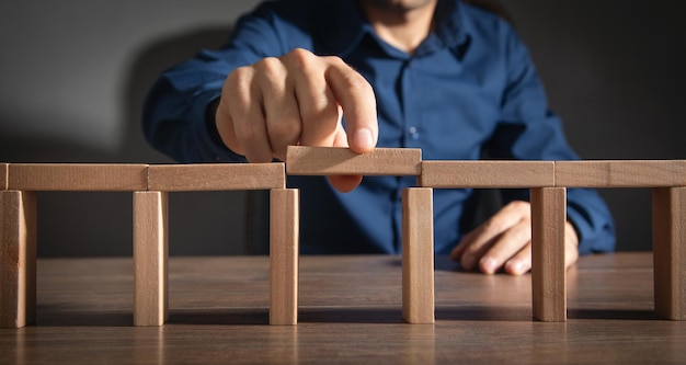 Uomo d'affari che monta un ponte fatto da blocchi di legno