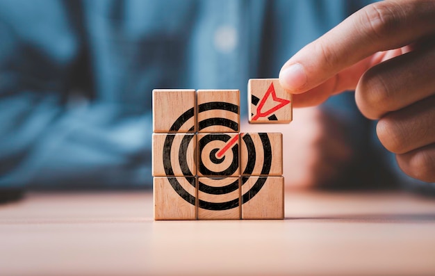 businessman assembly target board with arrow which printing on wooden cube block for set up business objective target and goal concept