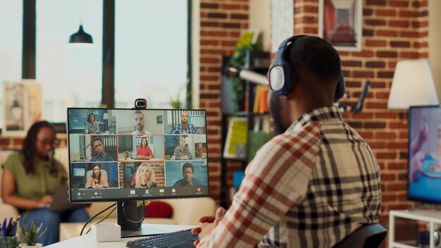 Foto uomo d'affari che partecipa a una riunione aziendale online sul computer con webcam, parlando con le persone in videoconferenza. utilizzo della teleconferenza remota per chattare su internet, lavorare da casa.