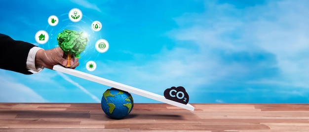 Businessman balance tree sprout on scale with co2 emission icon demonstrate esg or environment social governance commitment to carbon reduction through clean energy technology panorama reliance