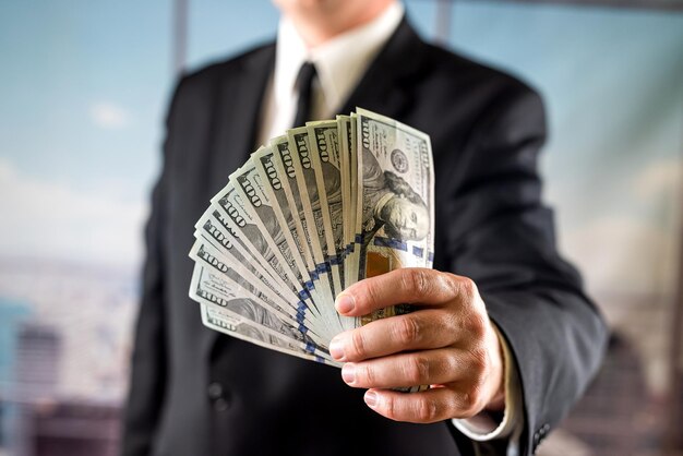 Businessman or bank employee counting one hundred dollar bills in front of him with his hands