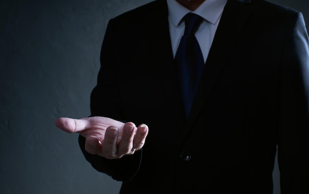 Businessman  in black suit lending a helping hand, isolated on white background