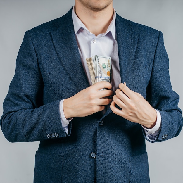 Businessman in a black suit putting money in his pocket