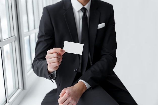 Businessman in black suit showing is card