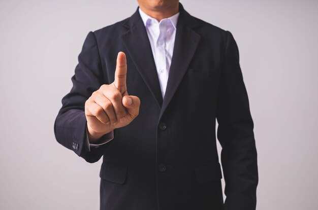 A businessman in a black suit stands and raises his hands