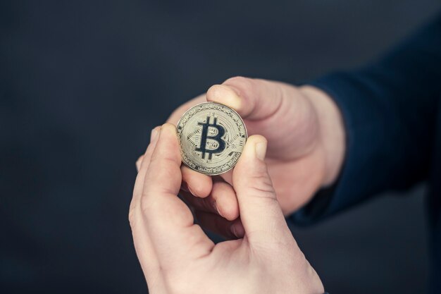 A businessman in a blue jacket holding Bitcoin in his hands.