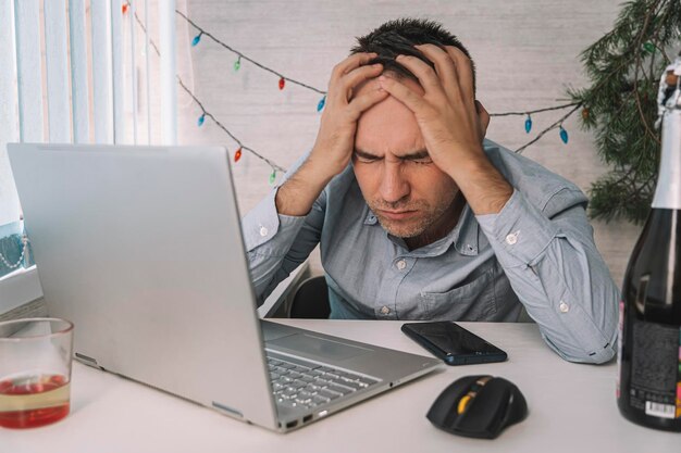 Businessman in blue shirt asleep at work with bottle of alcohol overslept because stormy night party with a drink after corporate on January 1 celebrated new year very bad hangover