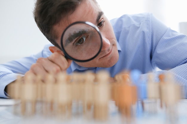 A businessman in blue shirt is holding a magnifying glass