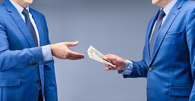 A businessman in a blue suit gives the other money