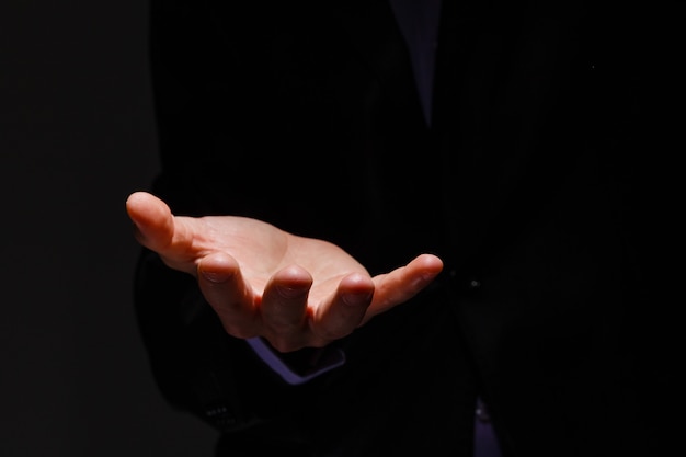 Businessman in blue suit presenting empty palm - it can be used
to advertise product on his hands.