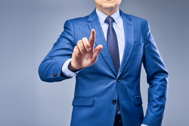 A businessman in a blue suit puts a finger in front of him