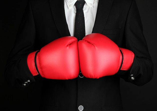 Businessman in boxing gloves isolated on black