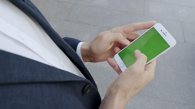 Foto uomo d'affari che naviga in internet sul telefono al di fuori del professionista utilizzando il cellulare