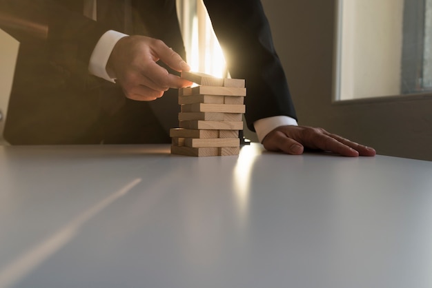 Photo businessman building a tower of wooden blocks