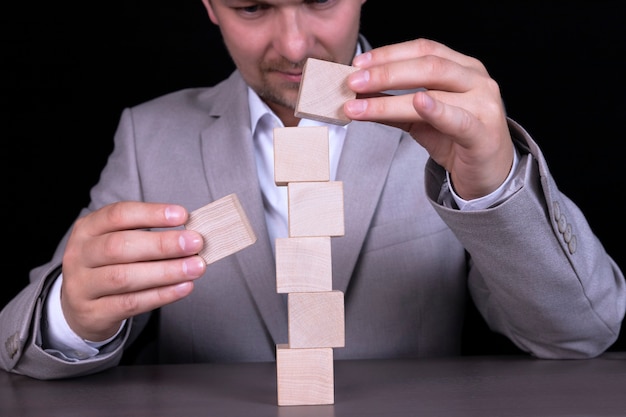 Foto un uomo d'affari costruisce una piramide di cubi di legno per scrivere una parola di sette lettere. copia spazio