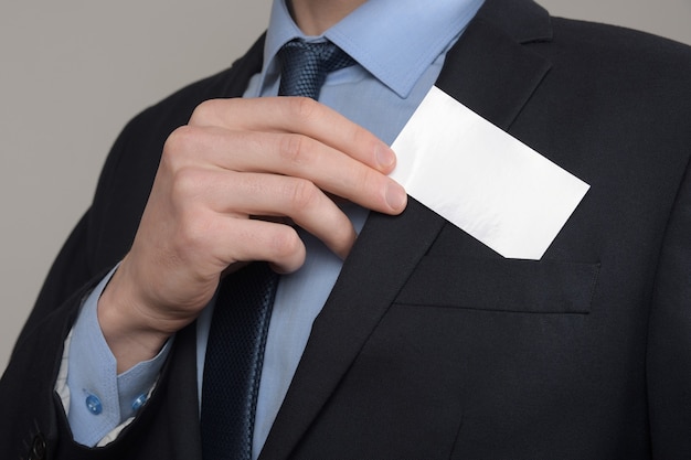 Businessman ,Business Man's hand hold showing business card - close up shot on grey background. Show a blank piece of paper. Paper visit card.