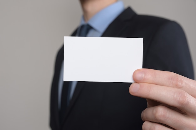 Businessman ,Business Man's hand hold showing business card - close up shot on grey background. Show a blank piece of paper. Paper visit card.