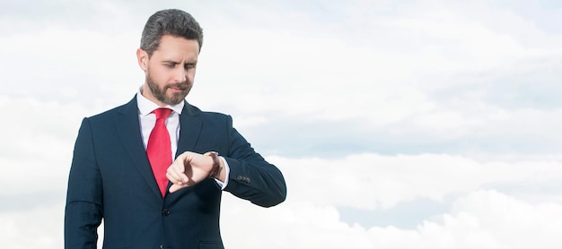 Businessman in businesslike suit checking time on sky background Man face portrait banner