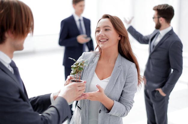 Businessman and businesswoman holding a pot with sprouts the concept of ecobusiness