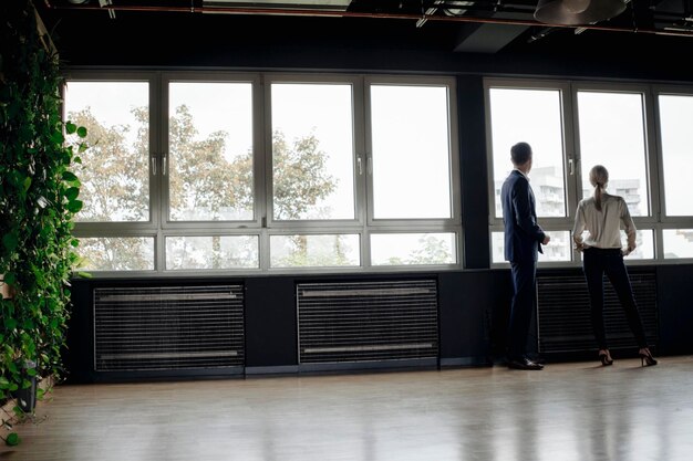 Businessman and businesswoman standing at the window