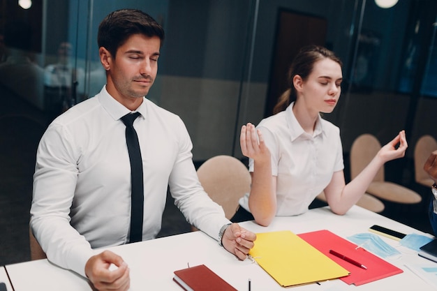 Businessman and businesswoman team meditate and holds hands
each other after office meeting business people group conference
discussion meditation concept