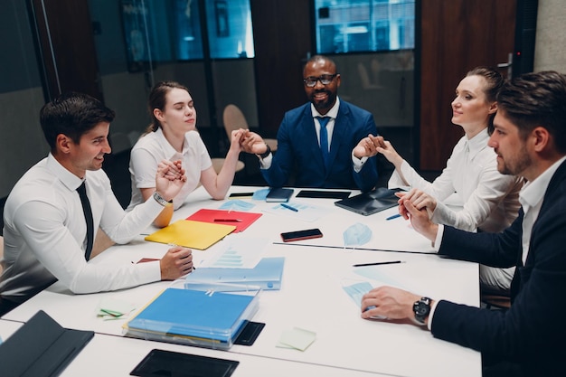 Businessman and businesswoman team meditate and holds hands\
each other after office meeting business people group conference\
discussion meditation concept