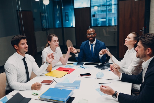 Businessman and businesswoman team meditate and holds hands each other after office meeting business...