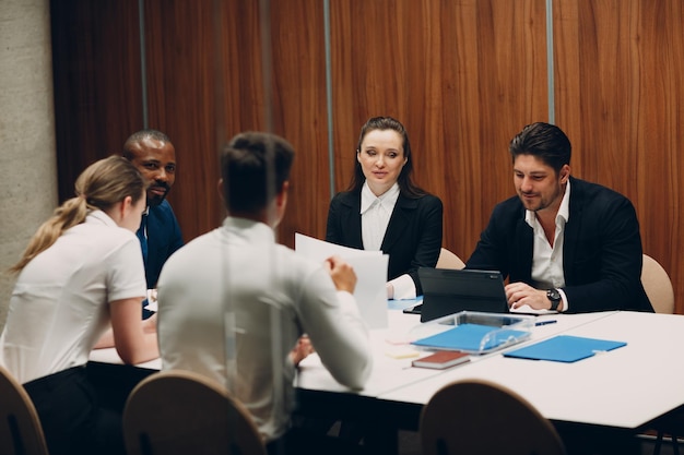 Businessman and businesswoman team at office meeting business\
people group conference discussion sit at table with boss man and\
woman