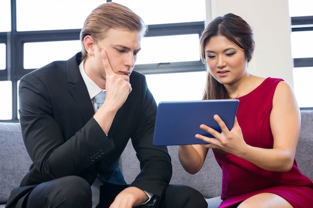 Uomo d'affari e donna di affari che utilizza compressa digitale nell'ufficio